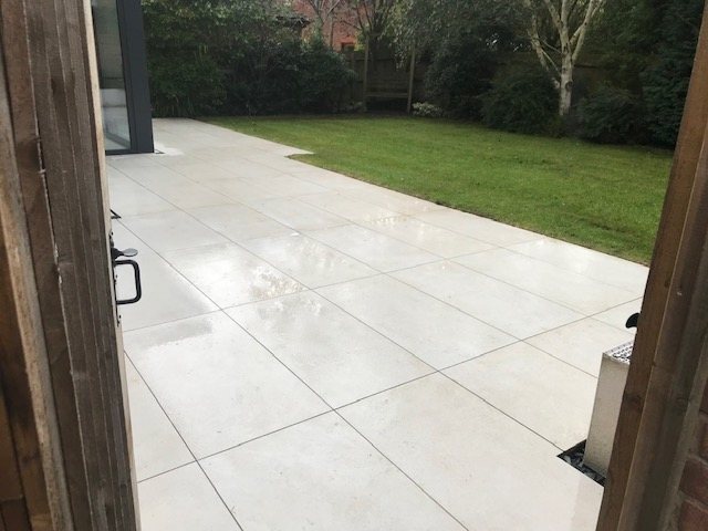 A large porcelain patio cleaned down and the garden beyond it cut and cleared — property maintenance rather than gardening, and just as much a part of the job.